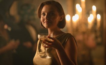 "Woman in a gold dress holding a drink at an elegant, dimly lit party with candlelight in the background, creating a warm, sophisticated atmosphere."